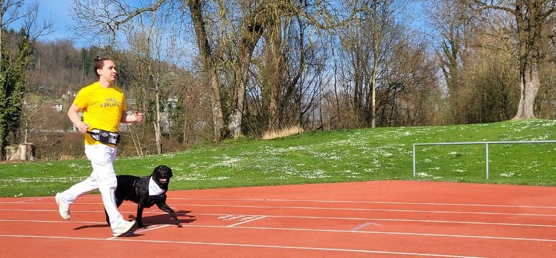 Un homme en train de courir, son chien guide est à ses côtés
