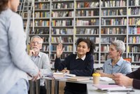 Plusieurs personnes suivent un cours, une participante lève la main
