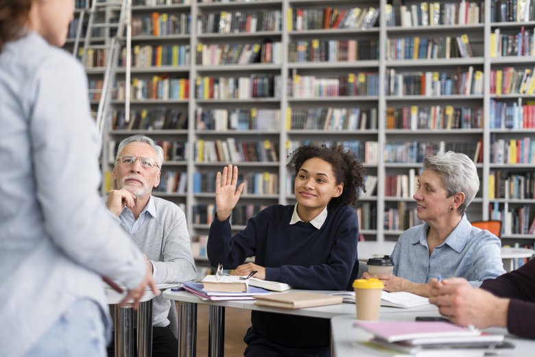 Plusieurs personnes suivent un cours, une participante lève la main