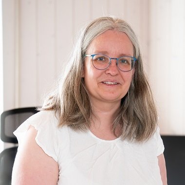 Katrin F. est vêtue d'un haut blanc et regarde la caméra