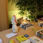 Documentation FRAGILE, ainsi qu'une statue représentant les conséquences des lésions cérébrales (offerte par une personne concernée) Table avec des brochures FRAGILE et une statue