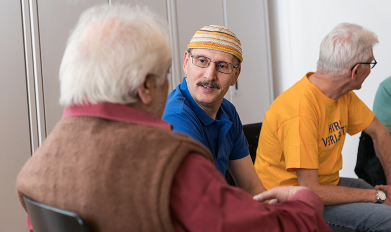 Prestations FRAGILE Suisse Extrait d'un groupe de parole. Une personne au premier plan tourne le dos à la caméra et est en conversation avec la personne à côté. La troisième personne est tournée vers une autre personne en dehors du cadre.